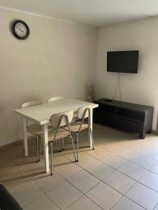 une table blanche et des chaises dans une pièce avec une télévision dans l'établissement L escapade nature, à Saint-Brès