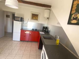 una cucina con armadi rossi e frigorifero bianco di Le Grimaubois a Hurbache