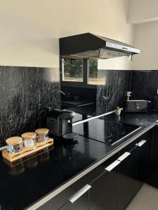 eine Küche mit einer schwarzen Arbeitsplatte und einer Mikrowelle in der Unterkunft F2 à 12 mn de Paris avec Sauna - Parking privé in Argenteuil