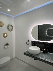 ein weißes Badezimmer mit Waschbecken und Spiegel in der Unterkunft F2 à 12 mn de Paris avec Sauna - Parking privé in Argenteuil