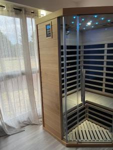 ein Zimmer mit einer Glasdusche mit einer Bank neben einem Fenster in der Unterkunft F2 à 12 mn de Paris avec Sauna - Parking privé in Argenteuil