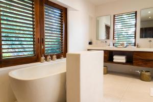 a bathroom with a tub and two sinks and a mirror at Playa Rosa Bungalows Careyes in Careyes