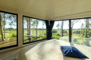a bedroom with a large bed and large windows at EstBerg Riverside Holiday Home in Räpina +17 photos