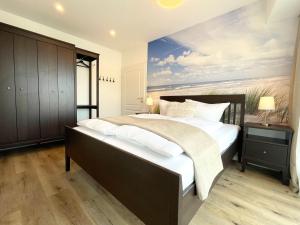 une chambre avec un grand lit avec un tableau au mur dans l'établissement Haus-Nordseebrandung-FeWo-9, à Cuxhaven