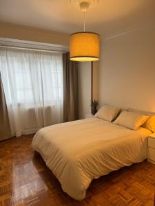 a bedroom with a large white bed with a light at As Travesas II in Betanzos