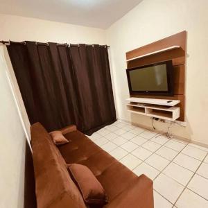 salon z kanapą i telewizorem z płaskim ekranem w obiekcie Ótima localização pertinho da orla da praia! w mieście Guarapari