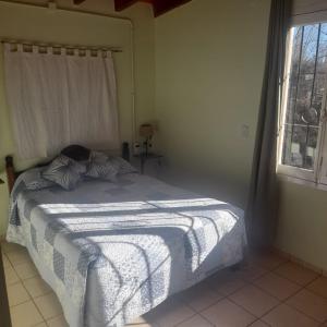 a bedroom with a bed with a white blanket and a window at La Normita cabañas in Potrerillos