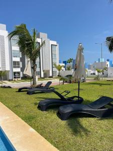 eine Reihe von Liegen auf dem Rasen in der Nähe eines Pools in der Unterkunft Cómodo depto Cerca al mar y cerca de Aeropuerto in Gallinero