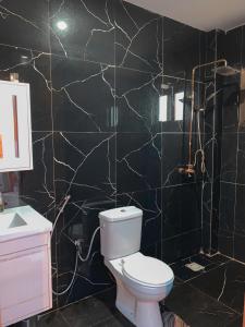 a bathroom with a toilet and a black tiled wall at Superbe appartement neuf aux Almadies 3 pièces in Dakar +19 photos