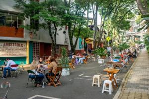 un grupo de personas sentadas en mesas en una calle en Bello alojamiento baño compartido en el Poblado-A5, en Medellín