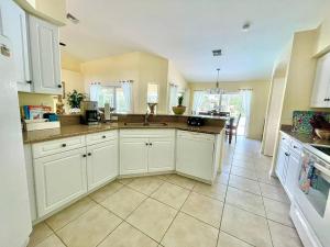 a kitchen with white cabinets and a tile floor at Villa Lahaina your perfect tropical getaway in Cape Coral