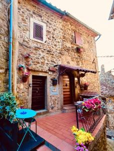 un bâtiment en pierre avec une table et des fleurs sur un patio dans l'établissement Maison Amiata, à Montelaterone