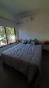 Cama grande en habitación con 2 ventanas en La Kaila, en Gualeguaychú