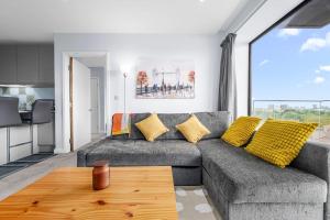 sala de estar con sofá gris y almohadas amarillas en Modern Apartment Central Manchester, en Mánchester