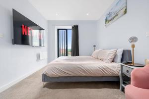 Un dormitorio con una cama, un televisor y una silla. en Modern Apartment Central Manchester, en Mánchester