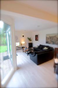 een woonkamer met een zwarte bank en een groot raam bij Holiday Home De Zuwe - Loosdrecht in Kortenhoef