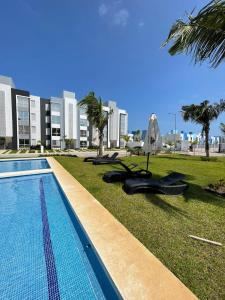 a resort swimming pool with chaise lounges and palm trees at Departamento completo cerca del Mar in Gallinero