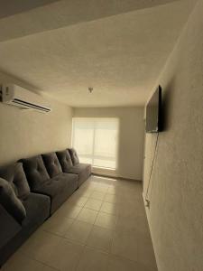 a living room with a couch and a television at Departamento completo cerca del Mar in Gallinero