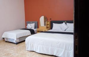 Una habitación de hotel con dos camas y un espejo. en New Bintang By Four-G, en Bajawa
