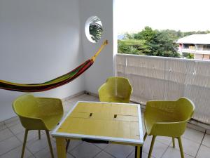 d'une terrasse avec des chaises, une table et un hamac. dans l'établissement COCON A JOJO, à Le Robert