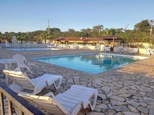 a swimming pool with white chairs and avisorvisorvisor at Casa com piscina, churrasqueira e ar condicionado em condomínio in Cabo Frio