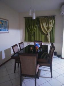 a dining room table with chairs and a green curtain at Apartamento Oktotoberfest Blumenau DAL in Blumenau