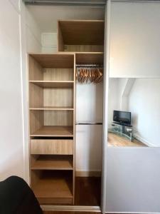 a closet with wooden shelves and a refrigerator at Studio confortable proche Paris in Châtillon