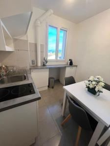 a kitchen with a sink and a table with flowers on it at Studio confortable proche Paris in Châtillon +6 photos