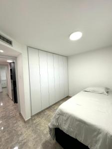 a bedroom with a bed and a white wall at Lujoso departamento en Playa el Angel in Pampatar