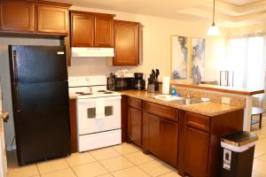 a kitchen with wooden cabinets and a black refrigerator at The Transient Stay #4 in Eagle Pass