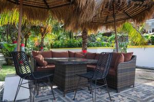 eine Terrasse mit einem Sofa und Stühlen unter einem Sonnenschirm in der Unterkunft Indah puri Bali Bungalow on Candidasa beach in Candidasa