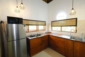 eine Küche mit Edelstahlkühlschrank und Holzschränken in der Unterkunft Indah puri Bali Bungalow on Candidasa beach in Candidasa