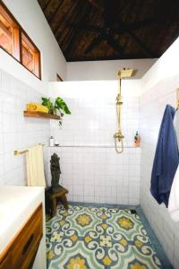 ein Bad mit Dusche und Fliesenboden in der Unterkunft Indah puri Bali Bungalow on Candidasa beach in Candidasa