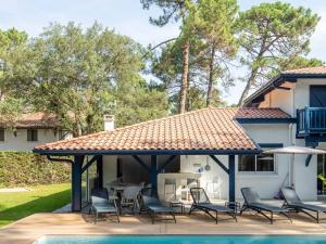 a pavilion with chairs and a table and a pool at Villa de luxe avec piscine chauffée, jacuzzi, sauna au cœur de la forêt des Landes - FR-1-791-24 in Soorts-Hossegor