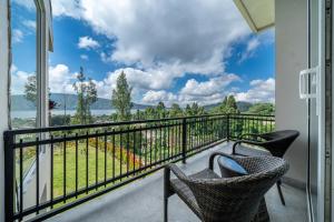 a balcony with two chairs and a view of the water at Adara Lake View Residence Bedugul - Bali in Bedugul