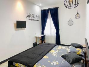 a bedroom with a bed and a tv and a window at Nan kanduang Homestay in Bukittinggi