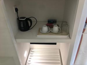 a cupboard with two cups and a coffee maker on a shelf at Saffron Robes Living in Hikkaduwa
