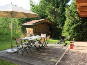 a table and chairs with an umbrella and a grill at Ferienhaus Hirschwiesn -565- in Krün