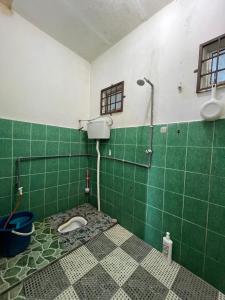 a green tiled bathroom with a toilet in it at AZ Homestay in Tanah Merah