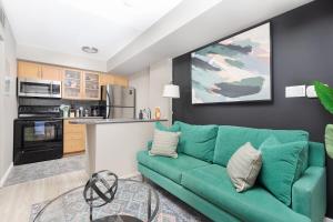 a living room with a green couch and a kitchen at Lakeside Haven - Cozy Townhome in Liberty Village in Toronto +8 photos
