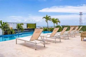 a row of chaise lounge chairs next to a swimming pool at Estudio de playa Monpal in Playa del Carmen