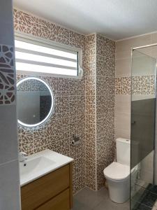 a bathroom with a toilet and a sink and a mirror at Pacifique Suite in Cayenne