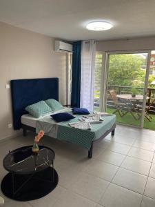a bedroom with a bed and a balcony with a table at Pacifique Suite in Cayenne