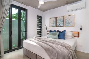 a bedroom with a large bed with blue pillows at Aria Villa 2 Port Douglas in Port Douglas