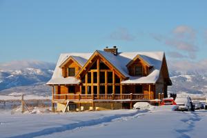 una casa de madera con nieve en el techo en Teton Hostel HideAway en Driggs