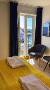 a bedroom with a bed and a chair and a window at Kragerø Hotell in Kragerø