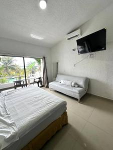 カンクンにあるSpacious Two-Story Apartment in Hotel Zone Central Location, Just 5 Minutes from Nightlife and Tourist Hotspotsのベッド、ソファ、薄型テレビのある寝室
