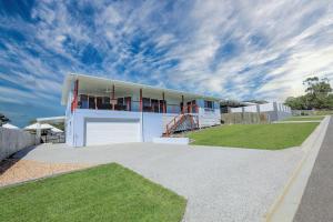 a white house with a garage on a lawn at Aquatic Abode in Agnes Water