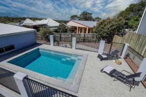 a swimming pool in a yard with chairs and a house at Aquatic Abode in Agnes Water