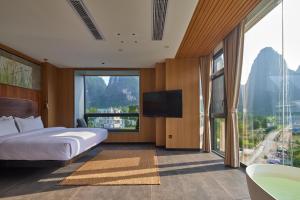 a bedroom with a bed and a television and a tub at Yangshuo The One Hotel- Aesthetic Lifestyle in Yangshuo
